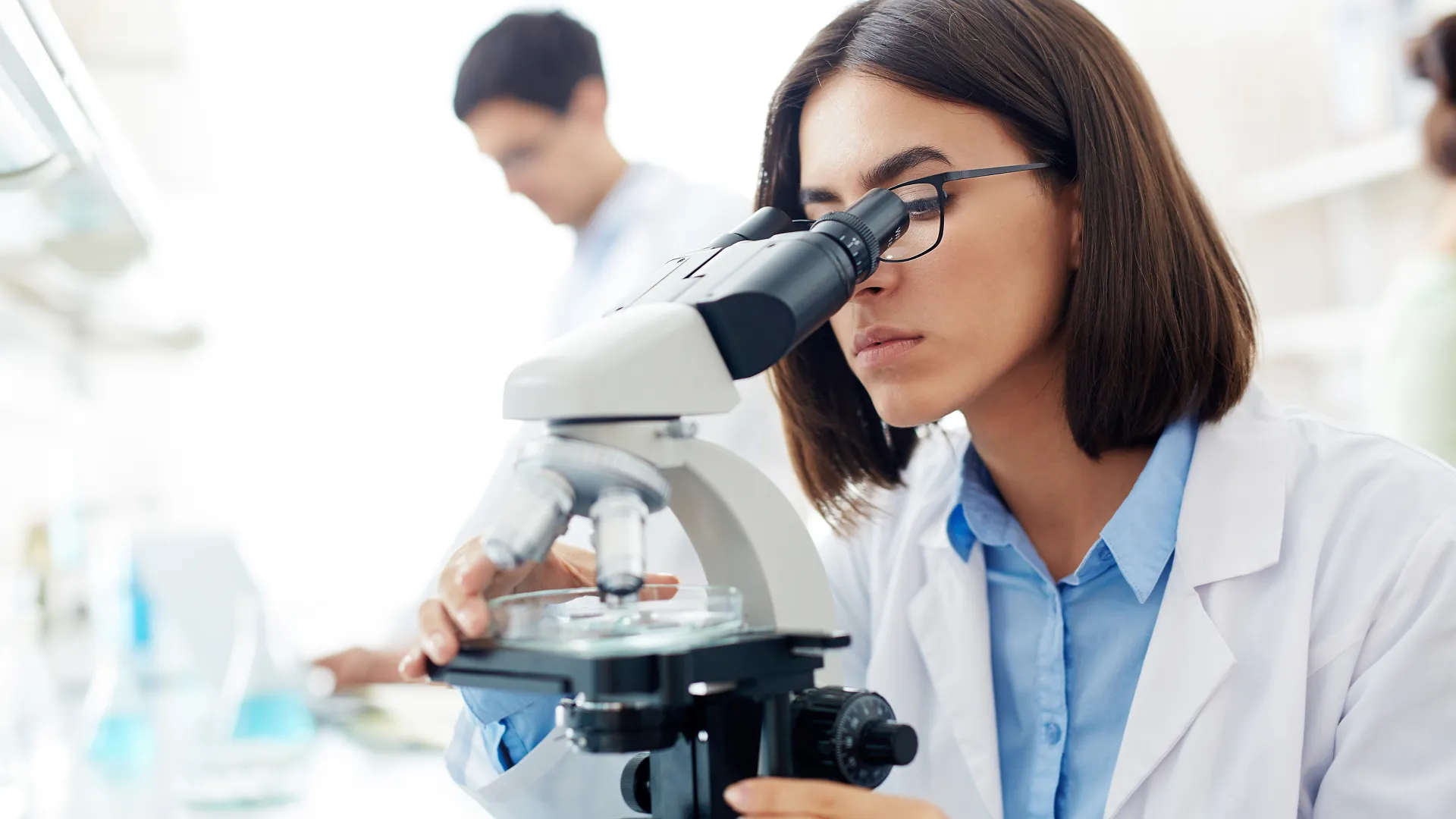 Scientist using a microscope during drug discovery target identification and lead optimisation research